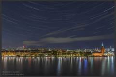 Stockholm is at a latitude of about 60°N. When you look northwards in the night sky, the pole star is very high up, two-thirds to the zenith. There is a lot of space between the pole star and the horizon below. Coming from the tropics, this seems a little out of place.Here are some polar star trails looking northwards from the vantage point of Skinnarviksberget. There is a small hillock, high standing rock at this location.  You can look till far beyond the Riddarfjärden. You can see the tall tower of the Stockholm Town Hall, and the typical pastel coloured copper painted buildings.